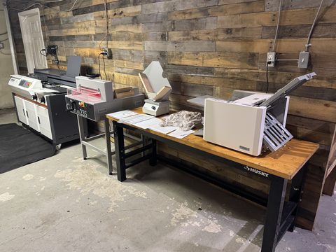 Side view of the print finishing workstation with the glue binder, cutter, folder and jogger