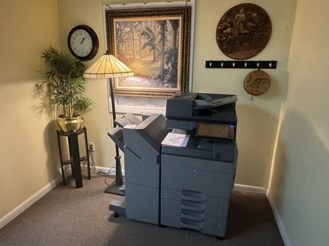 Production copier and printer in the print room beside a floor lamp and framed art